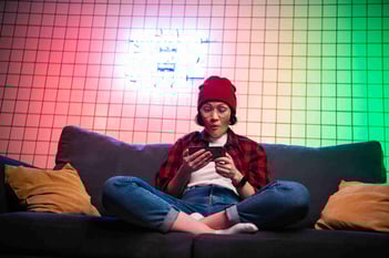 woman-watches-phone-while-sitting-on-couch