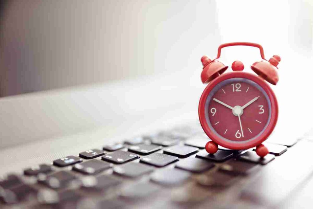 The alarm clock on the laptop indicates the importance of email campaign timing